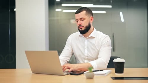 Focused Professional Working on Laptop in Modern Office