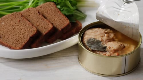 Canned fish with bread and greens close up