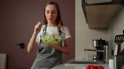 Woman Enjoys Fresh Salad in Modern Kitchen