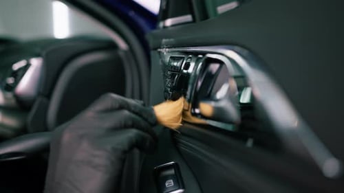 Car wash worker thoroughly cleaning the interior of a luxury car with a brush, gear box, detailing