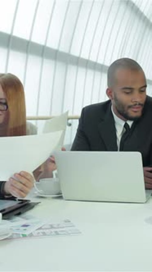 Team Discussing Business at Table with Laptop
