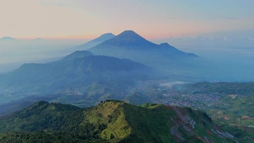 Fly over greenery mountain range in dawn with majestic mountains peaks and lush green valleys