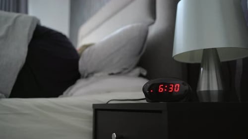Person in Bed Turns Off Alarm Clock