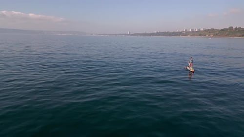 Aerial View of a Man Paddling a Standup Paddleboard or SUP Board on a Calm Sea