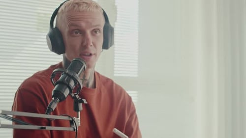 Man Speaking Into Microphone Writing on Clipboard
