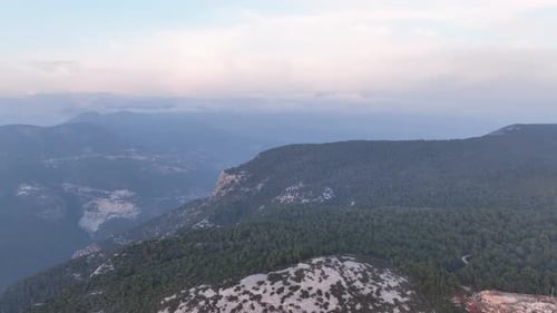 The Aerial Drone Moves Over Rocks and Dense Forest Mountain Landscape with a Path and Sky