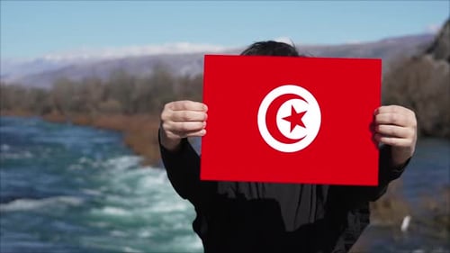 Person holding flag in front of river