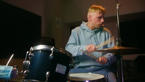 Drummer in Blue Hoodie Passionately Plays Drums in Music Studio Creative Energy Flows As He Captures
