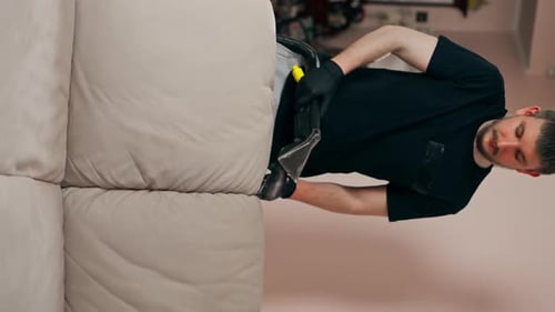 Man Cleaning Couch Cushions with Machine Indoors