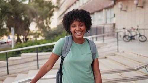 Woman Using Phone and Smiling on College Campus