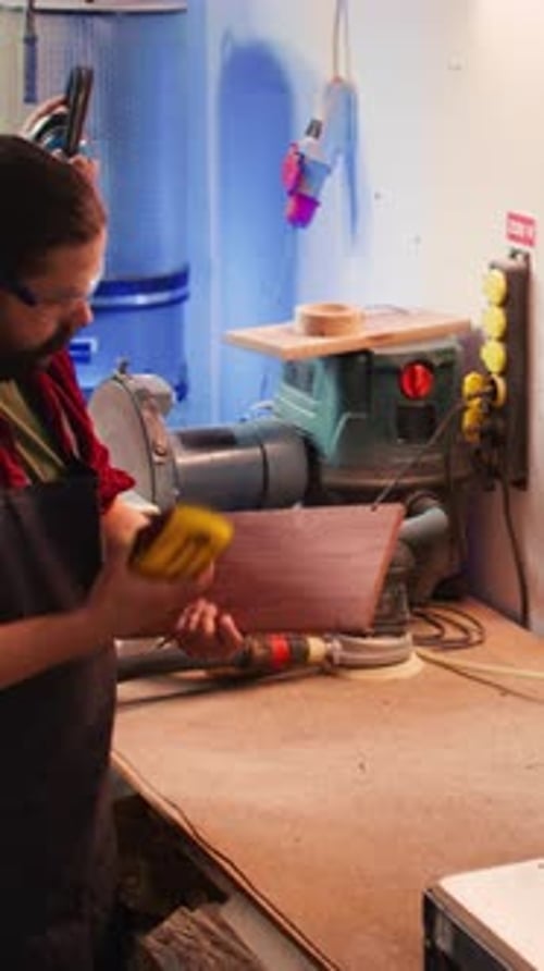 Vertical Video Artisan Next to Coworker Using Sanding Block to Remove Imperfections on Wood