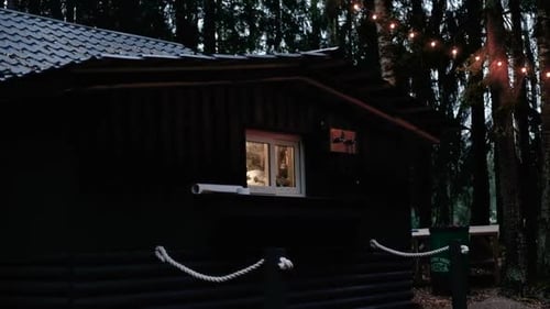 Dark Cabin with Lights in the Woods at Night