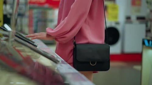 Lady in Pink Dress Interacting with Tablet Display Stand in Tech Store