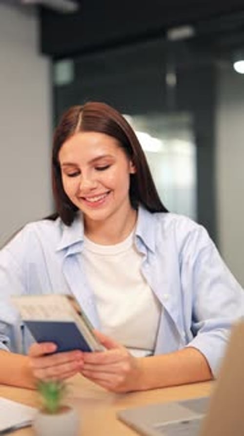 Woman Smiles Holding Passport at Office Desk