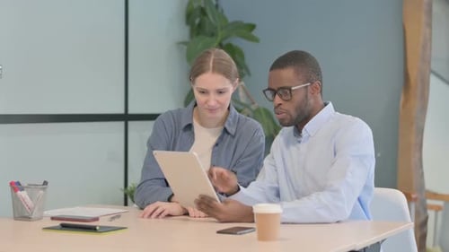Young Business People Discussing Work on Tablet in Office