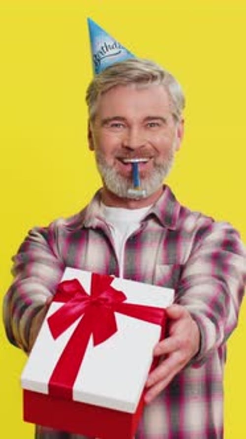 Mature Man Handing Presenting Birthday Gift Box Cone Hat Blower Joyful Expression Festive Atmosphere