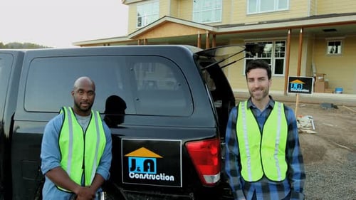 Construction Workers Stand Near Truck in Suburban Setting