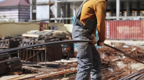 Worker Organizing Steel Reinforcement Rods at Construction Site