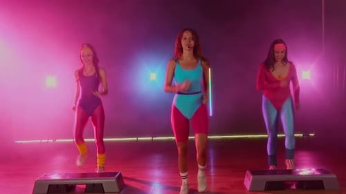 Happy Young Women Beginning 1980s Step Aerobics Workout in Neon Studio