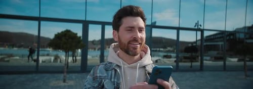 Man Smiling Using Phone in Urban Environment