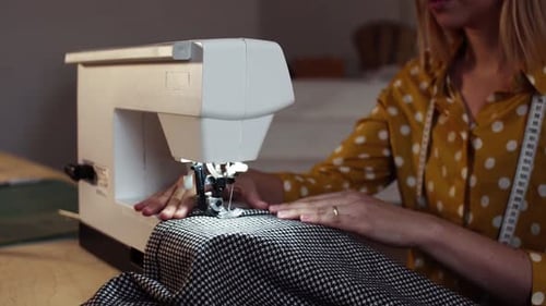 Young woman sewing fabric in bright studio startup business