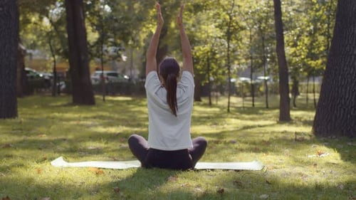 Woman Practices Yoga Outdoors in City Park