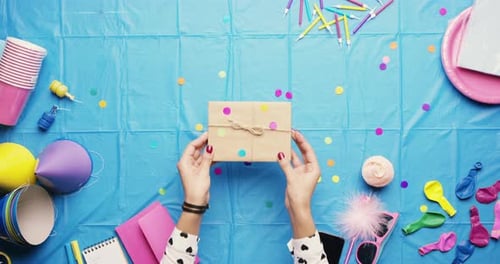 Hands, party table and box for present in closeup for decoration, confetti or balloons for birthday