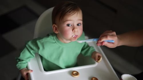 Infant Eating Yogurt from a Spoon in Highchair