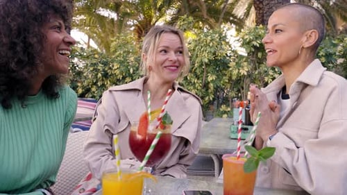 Friends Laughing Together at Tropical Cafe with Drinks