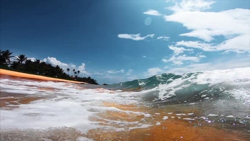 Ocean wave breaks over the sandy tropical beach