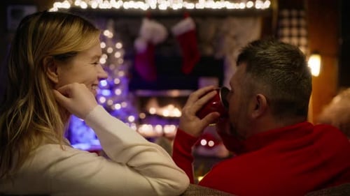 Couple Celebrating Christmas By The Fireplace At Home