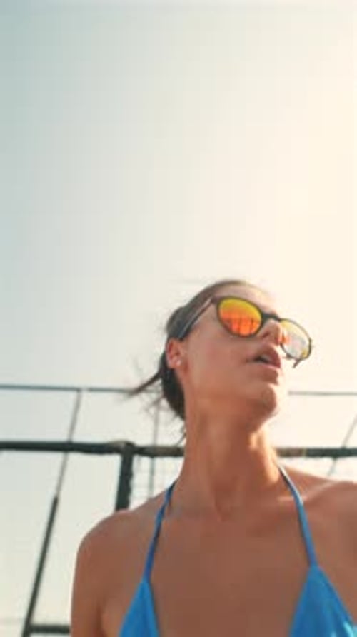 A Young Beautiful Girl in Glasses and a Bikini Jumps on the Beach