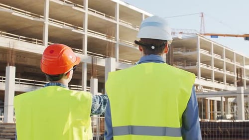 Professional Builders Standing in Front of Construction Site Office Building and Crane Background