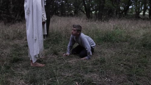Crying, praying teenage boy looks up at Jesus Christ wearing a white robe standing next to him