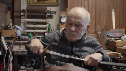 Senior Gray Haired Male Master in a Wheelchair Working at His Workshop Restoring Japanese Sword