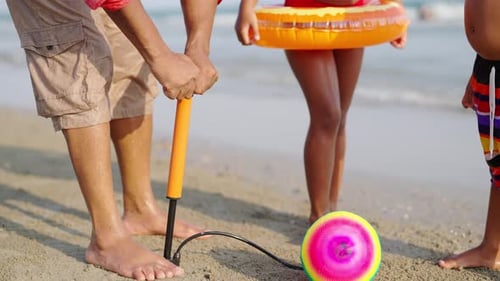 4K African Father playing ball with little daughter and son on tropical beach at summer sunset.