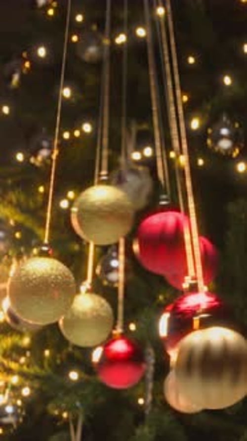 Christmas Ornaments Hang on Tree Lit with Lights