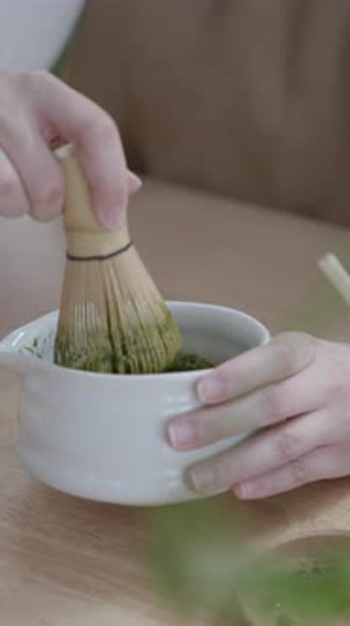 Preparing matcha tea with a bamboo whisk
