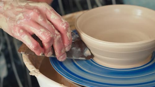 Une potière travaille sur un tour de potier et fabrique un pot en céramique en argile dans un atelier de poterie.