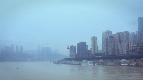 A ropeway cable car carries people across the river from the city above to the city below