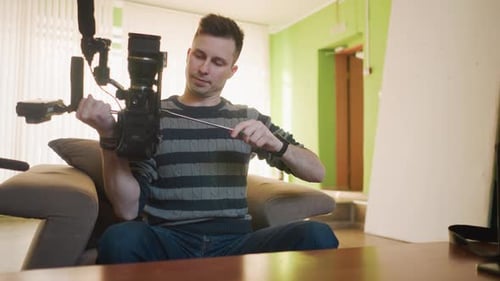 Man Adjusting Professional Camera and Tripod Indoors