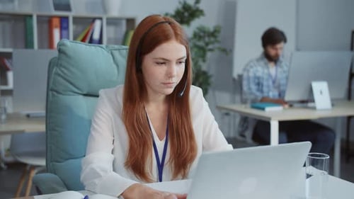 Une femme assise à un bureau moderne concentrée sur son ordinateur portable incarne le travail à distance