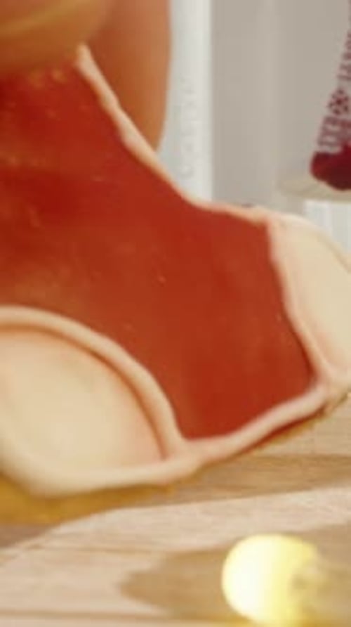 Vertical video. A Close-Up of a Hand Picking Up a Red Stocking-Shaped Cookie, Surrounded by Various
