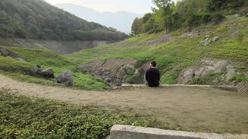 Young Adult Sitting in Green Mountain Valley