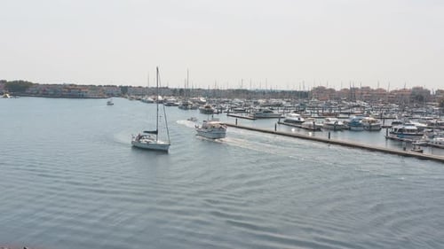 Cinematic drone / aerial panorama shot of a marina with sailing boats two boat sailing in the foregr