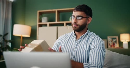 Man Smiles with Package and Laptop at Home