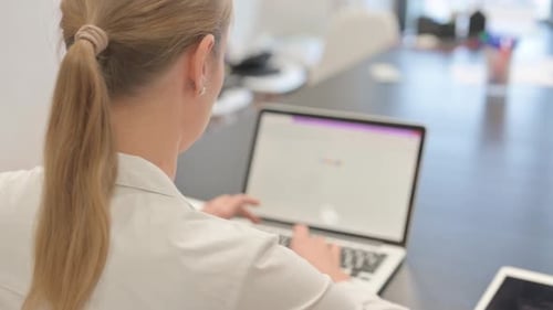 Mujer de negocios escribiendo en el ordenador portátil, vista trasera
