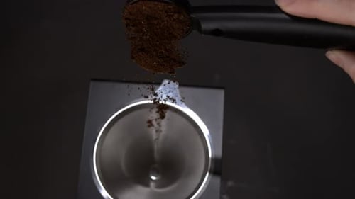 Coffee falling out of a coffee spoon into a pour over coffee maker in super slow motion