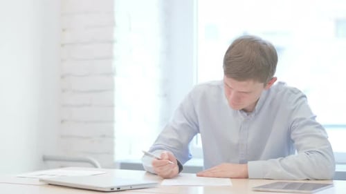 Frustrated Young Businessman Trying to Write in Office
