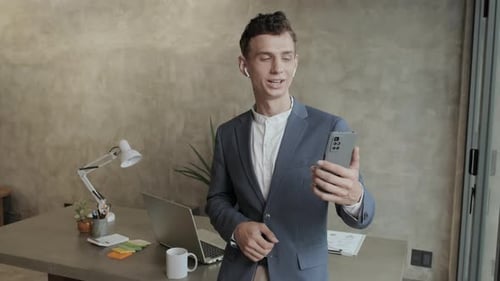 Young Adult in Suit Waving During Video Conference